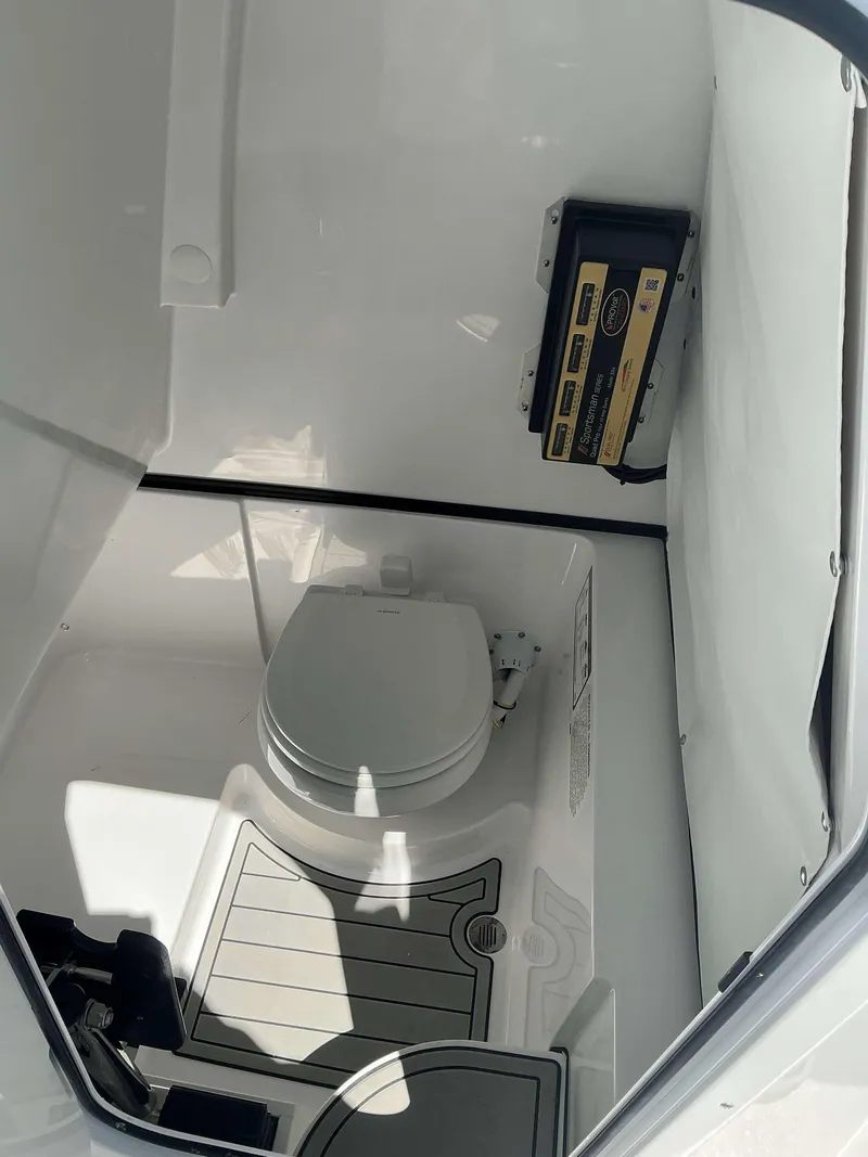 Slide: The Image of Interior of 2025 Sportsman 261 Heritage boat featuring a compact marine toilet. - 21