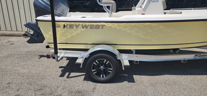 Slide: The Image of 2024 Key West 1720CC boat on trailer, side view, yellow hull, parked outdoors. - 3