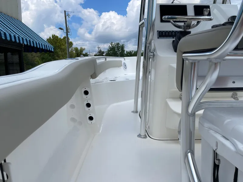Slide: The Image of 2025 Key West 203FS boat interior with steering console and seating, under a partly cloudy sky. - 27