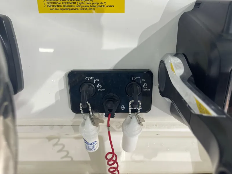 Slide: The Image of 2024 Key West 244CC boat ignition panel with dual start switches and safety lanyards. - 26