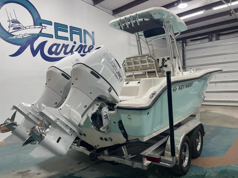 Slide: The Image of 2024 Key West 244CC boat with dual Suzuki engines on a trailer in a showroom. - 7