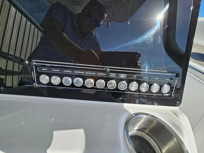Slide: The Image of Control panel of 2025 Tidewater 220LXF boat with various switches and cup holder. - 16