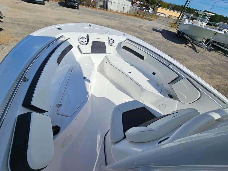 Slide: The Image of 2025 Tidewater 220LXF boat interior with seating and speakers, parked outdoors. - 21