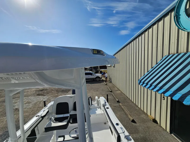 Slide: The Image of 2025 Tidewater 220LXF boat parked near a building under a clear blue sky. - 23