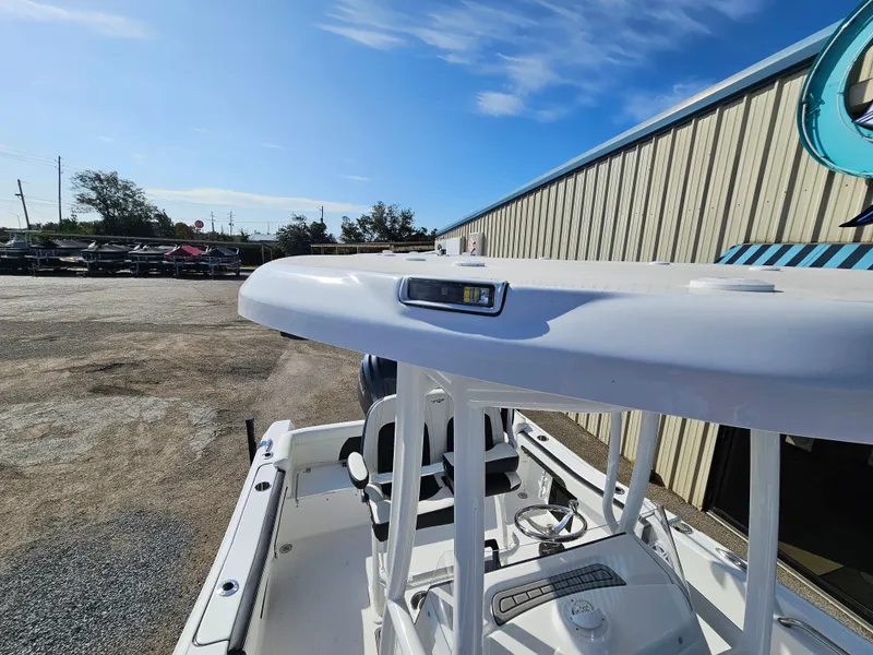 Slide: The Image of 2025 Tidewater 220LXF boat with T-top, parked outdoors under clear sky. - 24
