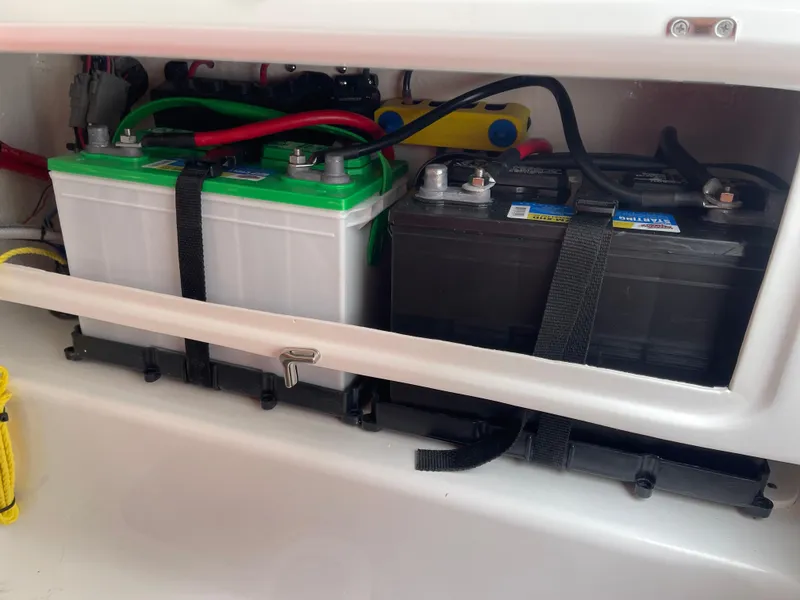 Slide: The Image of 2025 Tidewater 232cc boat battery compartment with dual batteries and secure straps. - 34