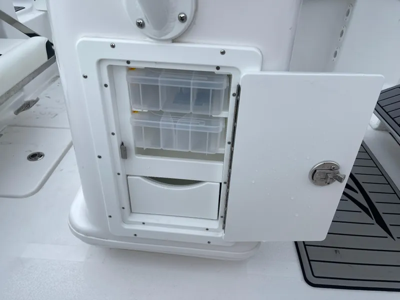 Slide: The Image of 2025 Tidewater 232cc boat storage compartment with open door and organized containers. - 42