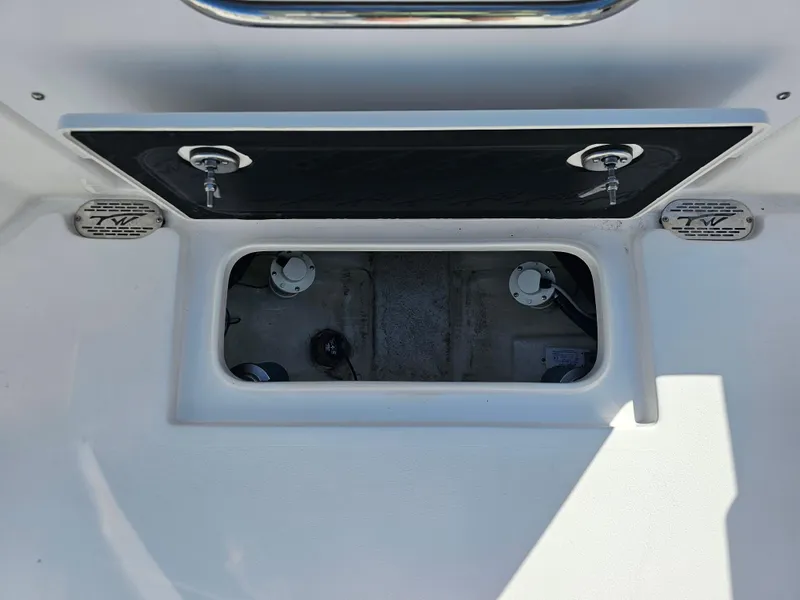 Slide: The Image of 2024 Tidewater 272cc boat storage compartment with secure latches and TW branding. - 10