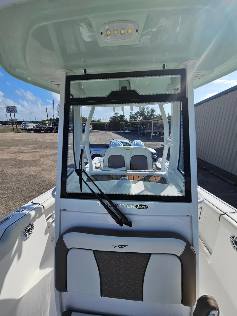 Slide: The Image of 2024 Tidewater 272cc boat interior with windshield and seating, parked outdoors. - 35