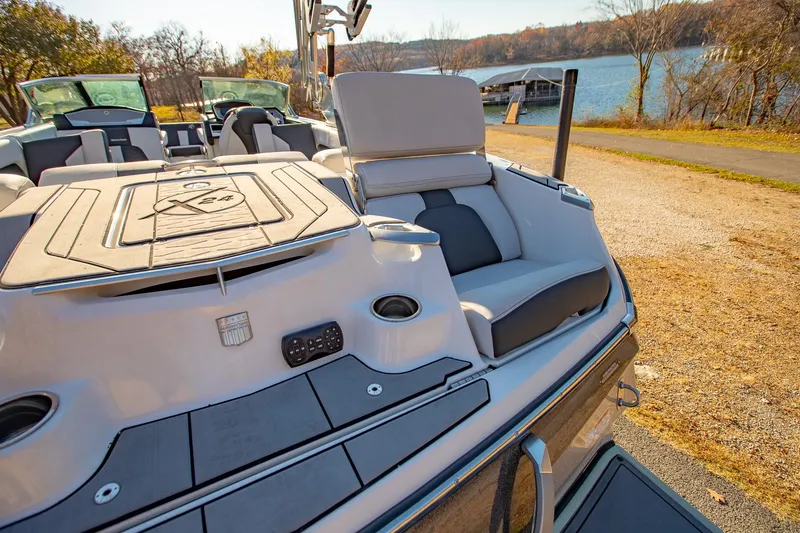 Slide: The Image of 2019 MasterCraft X24 boat with luxurious seating, docked by a scenic lake. - 13