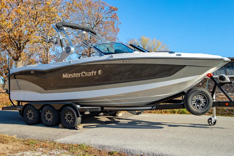 Slide: The Image of 2019 MasterCraft X24 boat on trailer, parked outdoors on a sunny day. - 2