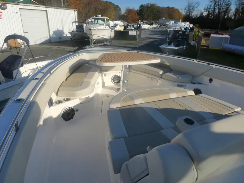 Slide: The Image of 2025 Boston Whaler 420 Outrage boat interior with seating and table in marina setting. - 10