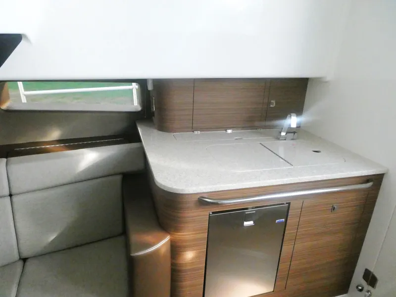 Slide: The Image of Interior of 2025 Boston Whaler 420 Outrage, featuring modern kitchenette and seating area. - 19