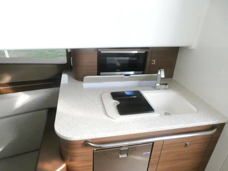 Slide: The Image of 2025 Boston Whaler 420 Outrage interior kitchen with sink, countertop, and microwave. - 20