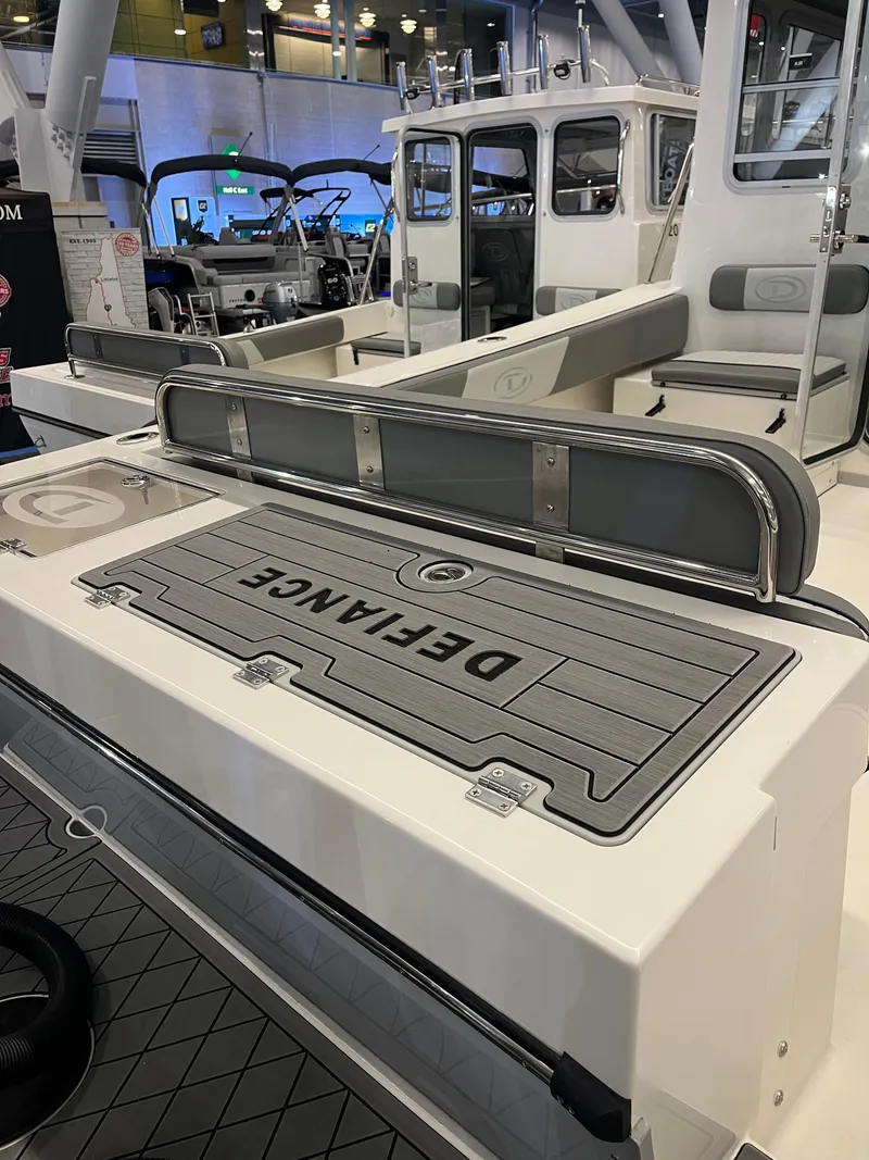 Slide: The Image of 2025 Defiance Admiral 260 EX boat interior at a showroom, showcasing seating and deck design. - 2