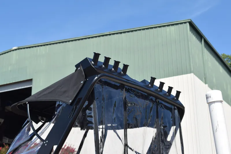 Slide: The Image of 2025 Stabicraft 1550 Fisher Profish boat with rod holders, against a green building backdrop. - 6