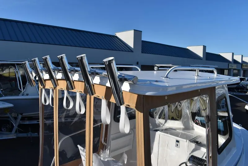 Slide: The Image of 2025 Steiger Craft 21 Peconic boat with rod holders and cabin, docked under clear sky. - 15