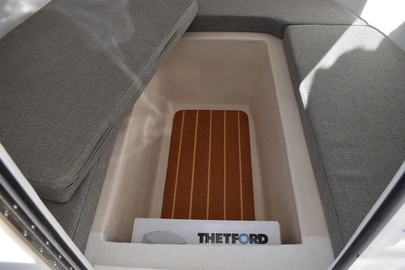 Slide: The Image of 2025 Steiger Craft 21 Peconic interior seating with storage compartment and Thetford accessory. - 46