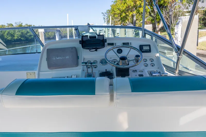 Slide: The Image of 1995 Cruisers Esprit 3570 boat helm with teal and white seating, docked by a river. - 11