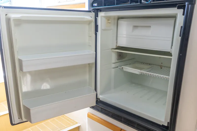 Slide: The Image of Open refrigerator inside 1995 Cruisers Esprit 3570 boat, showing empty shelves and freezer compartment. - 32