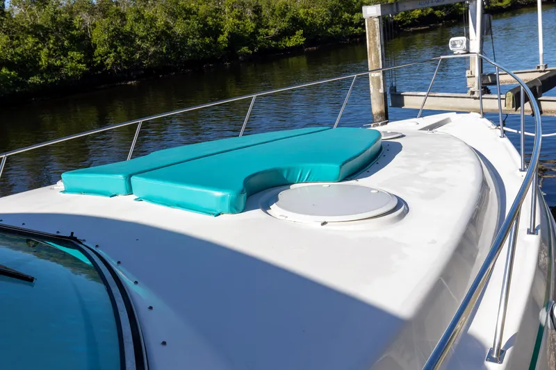 Slide: The Image of 1995 Cruisers Esprit 3570 yacht with teal cushions docked by a river. - 4