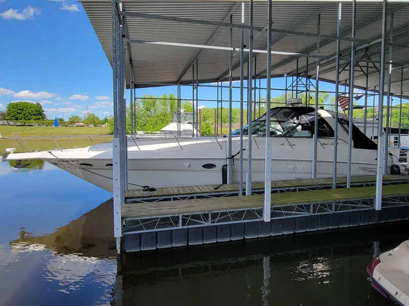 Slide: The Image of 2000 Sea Ray 460 Sundancer docked under a covered marina on a sunny day. - 2