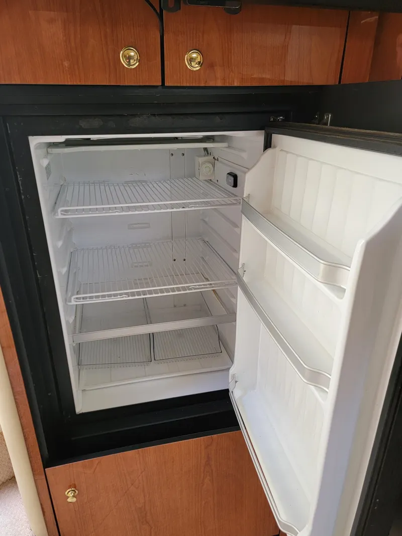 Slide: The Image of Open refrigerator inside 2000 Sea Ray 460 Sundancer yacht, featuring wooden cabinetry. - 43