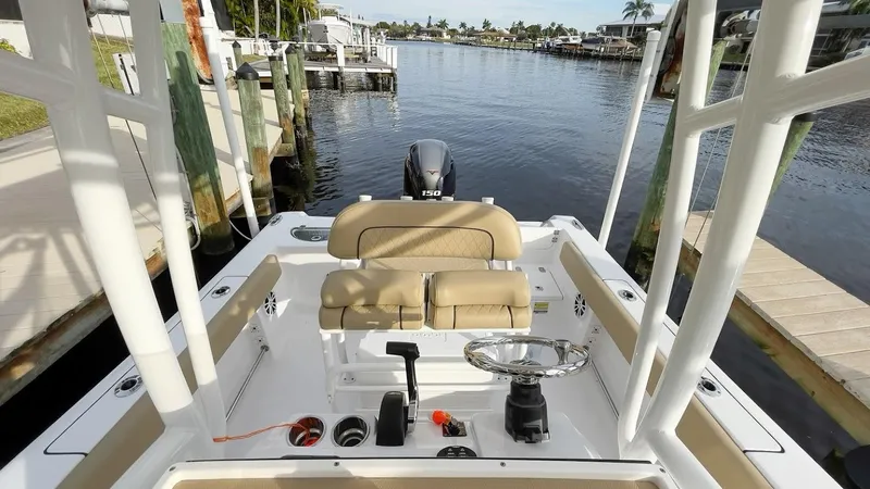 Slide: The Image of 2018 Sportsman Open 212 boat interior with steering wheel and seating, docked by a canal. - 11