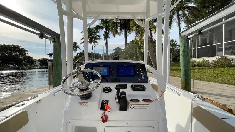 Slide: The Image of 2018 Sportsman Open 212 boat dashboard with steering wheel and navigation screens, docked by palm trees. - 9