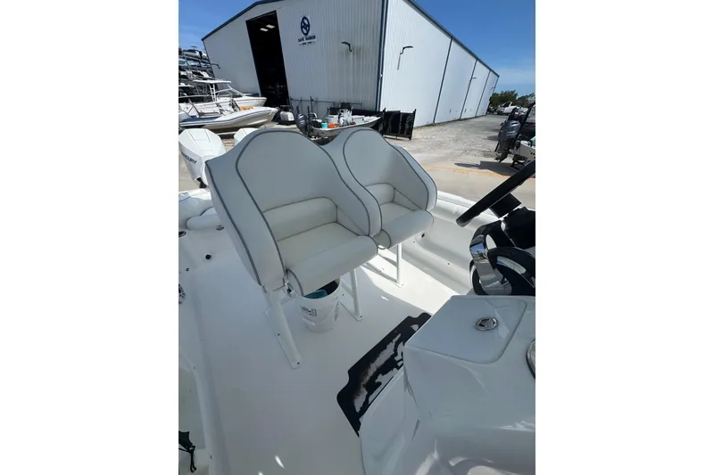 Slide: The Image of 2021 Glasstream 280 Pro-XS boat with dual white cushioned seats, docked near a storage facility. - 8