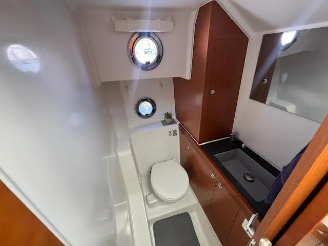 Slide: The Image of 2016 Beneteau Swift Trawler 30 bathroom with porthole, toilet, and sink. - 8