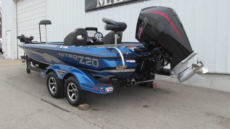 Slide: The Image of 2025 Nitro Z20 XL Pro boat with trailer, blue and black design, parked outdoors. - 2