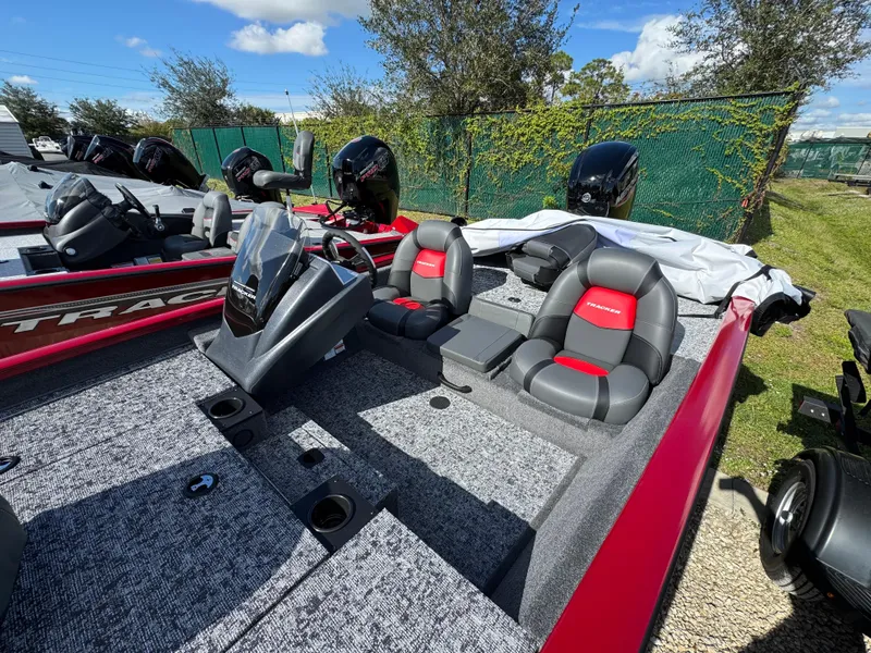 Slide: The Image of 2025 Tracker Pro Team 175 boat with red and gray seating, parked outdoors. - 2