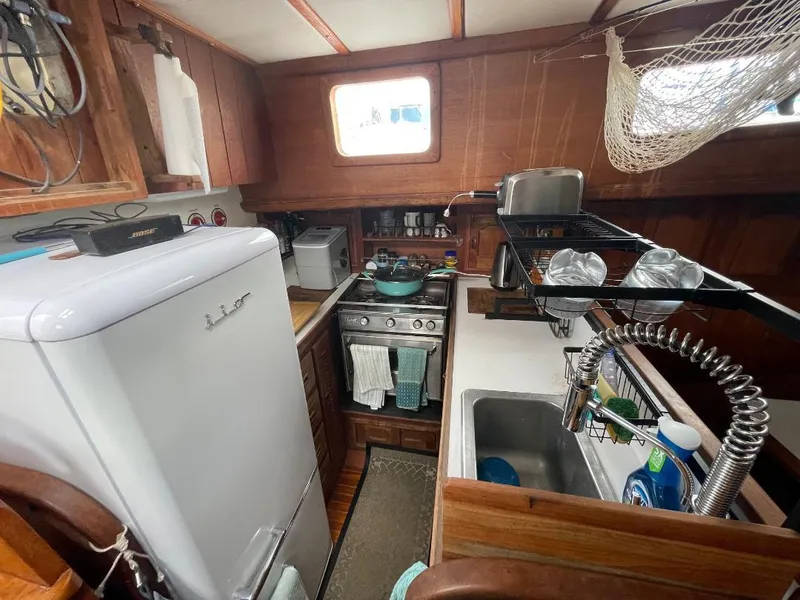 Slide: The Image of 1979 C & L Explorer Center Cockpit Cutter kitchen with stove, sink, and wooden cabinetry. - 11