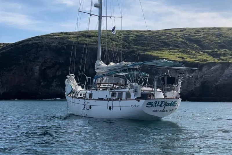 Slide: The Image of 1979 C & L Explorer Center Cockpit Cutter sailboat anchored near rocky coastline. - 2