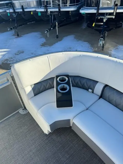 Slide: The Image of 2024 Bennington 25 QFB boat interior with cushioned seating and dual cup holders. - 19