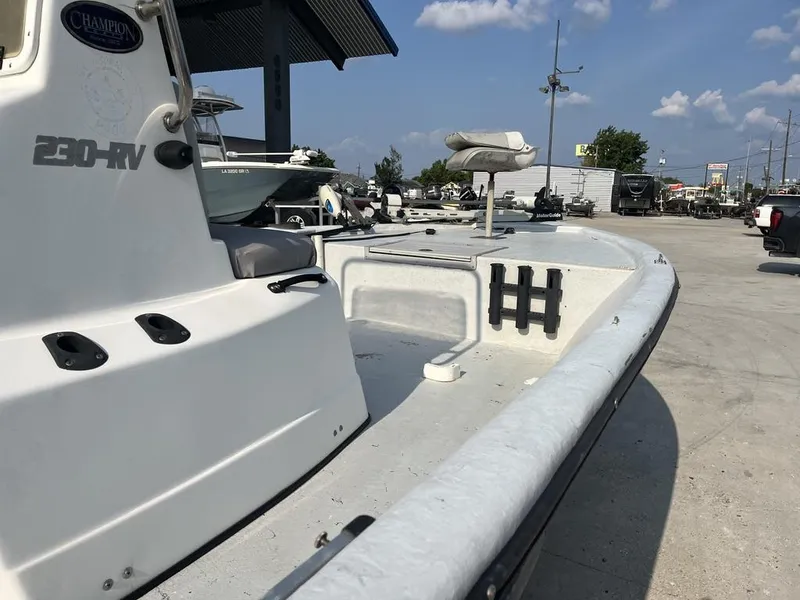 Slide: The Image of 2002 Champion 230-RV boat interior with fishing rod holders and seat under sunny sky. - 11