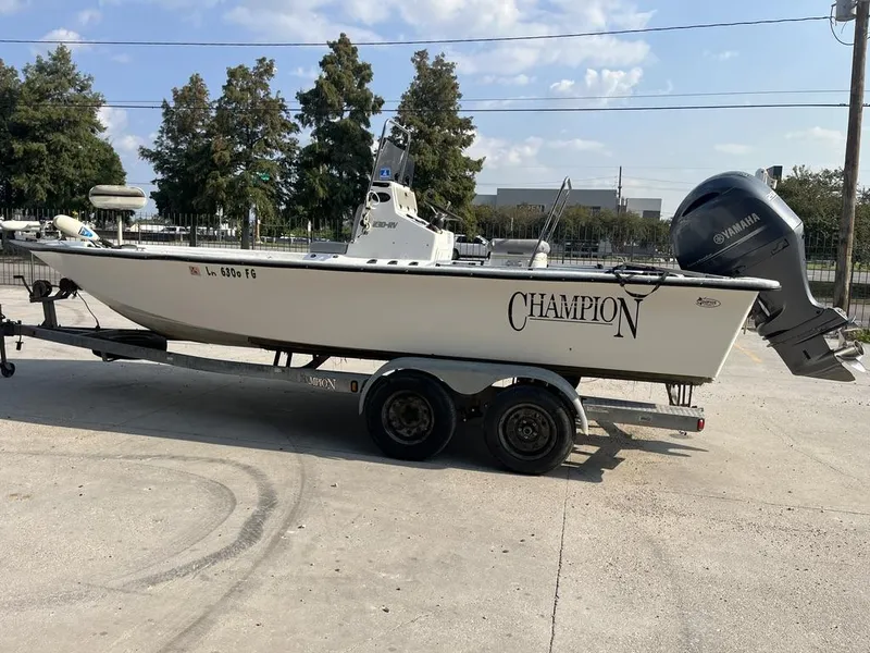 Slide: The Image of 2002 Champion 230-RV boat interior with seating and console, parked outdoors. - 6