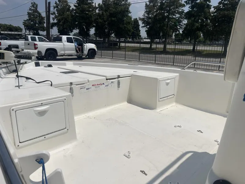 Slide: The Image of 2000 Robalo boat interior with storage compartments, parked near white trucks and trees. - 12