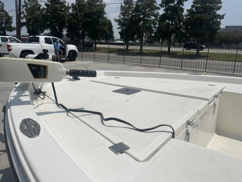 Slide: The Image of 2000 Robalo boat deck with trolling motor, parked near white trucks and trees. - 13