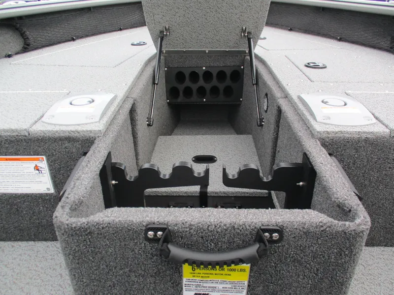 Slide: The Image of 2025 Lund Pro Guide 1875 boat storage compartment with rod holders and safety labels. - 16