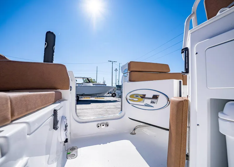 Slide: The Image of 2025 Sea Hunt Ultra 255 SE boat interior with brown seating under clear blue sky. - 11