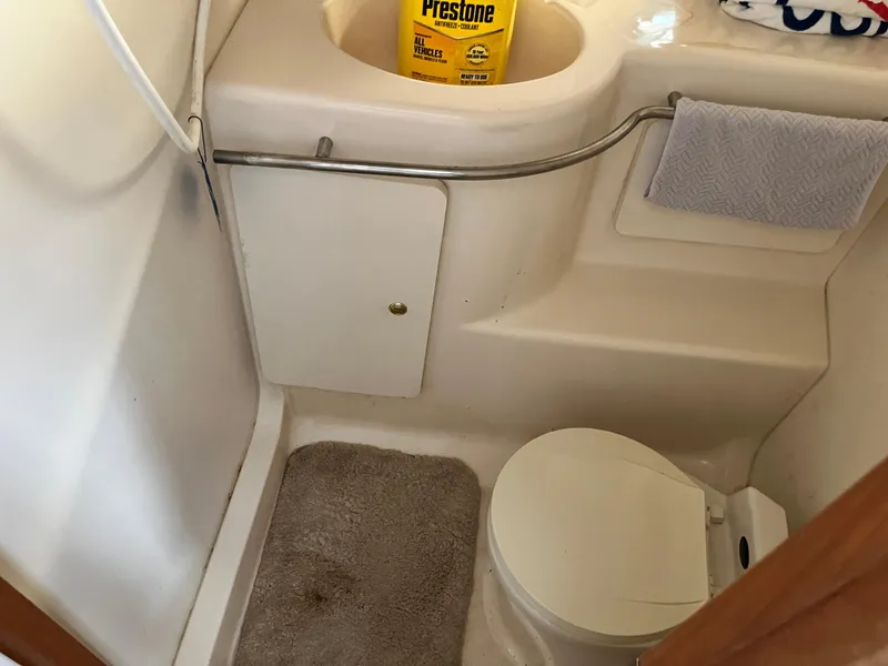 Slide: The Image of 1998 Silverton 322 Motor Yacht bathroom with toilet, sink, and cleaning supplies. - 10