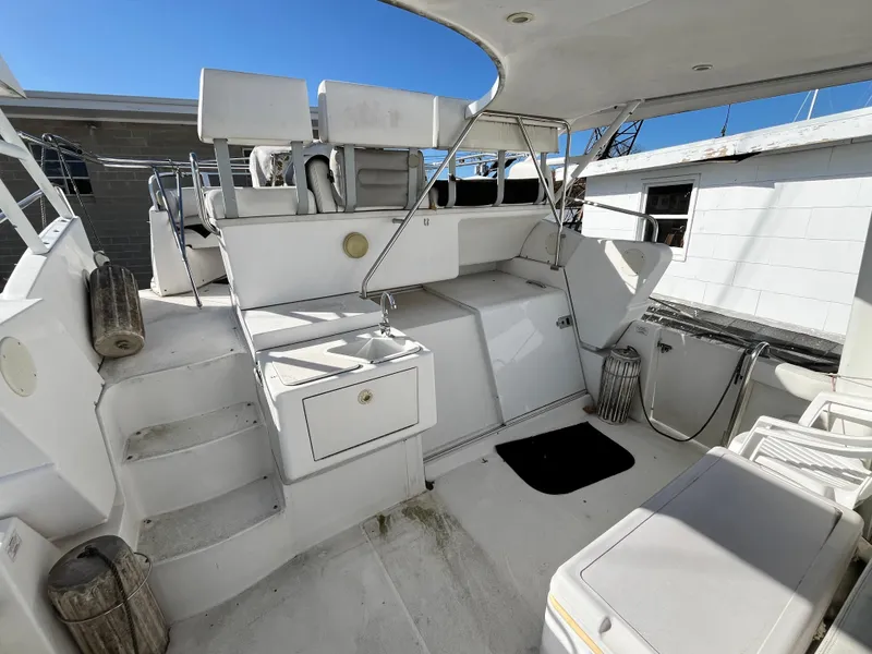 Slide: The Image of 1998 Silverton 322 Motor Yacht interior with seating and stairs, under clear blue sky. - 5