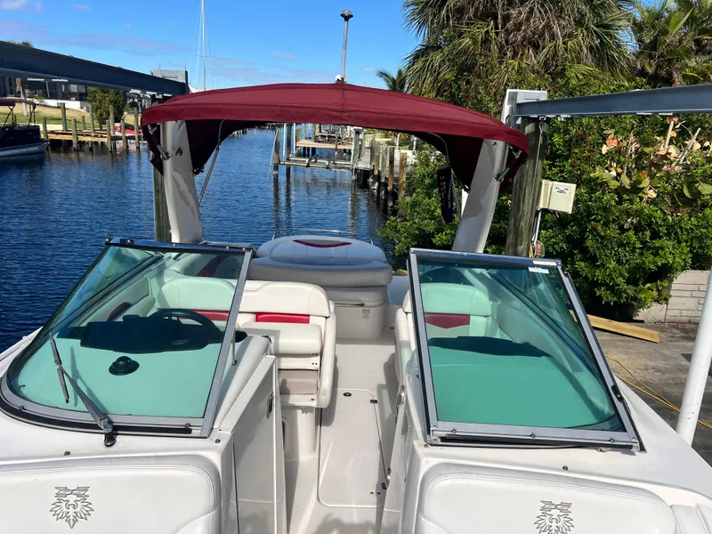 Slide: The Image of 2015 Chaparral 287 SSX boat with red canopy docked by a scenic waterfront. - 13