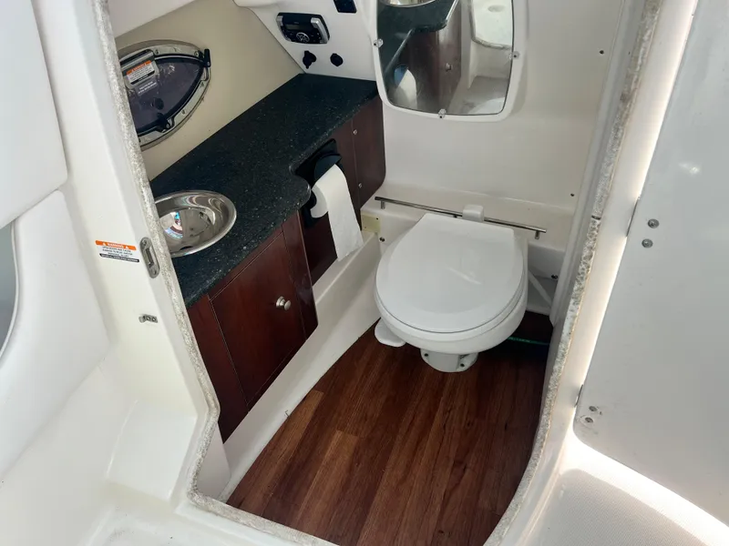Slide: The Image of 2015 Chaparral 287 SSX boat bathroom with sink, toilet, and wood flooring. - 14