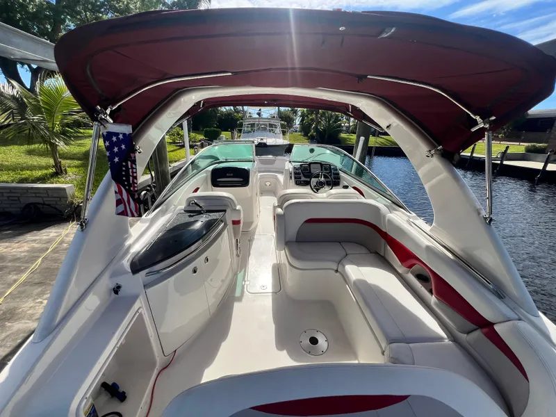 Slide: The Image of 2015 Chaparral 287 SSX boat interior with red canopy and seating, docked by a canal. - 4