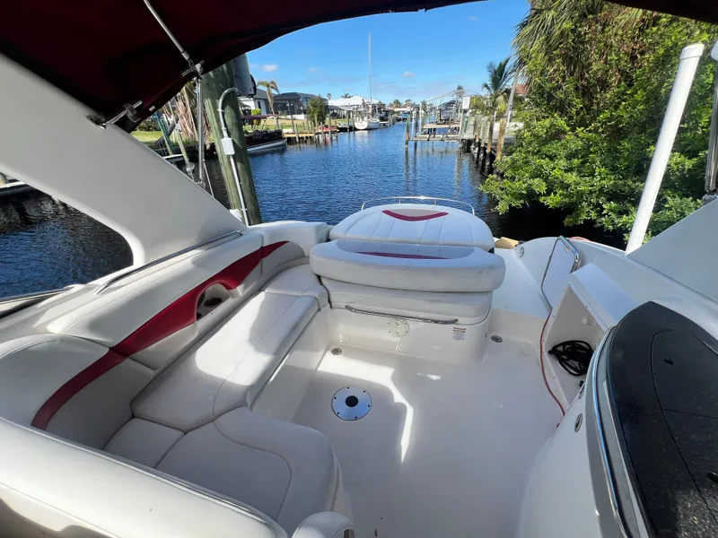 Slide: The Image of 2015 Chaparral 287 SSX boat interior with white and red seating by a scenic waterfront. - 5