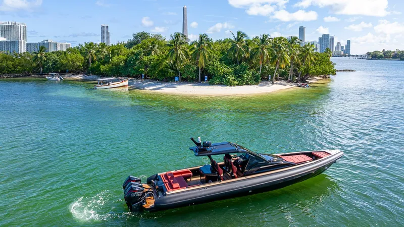 Slide: The Image of 2025 Technohull Omega 47 cruising near tropical island with city skyline in background. - 2