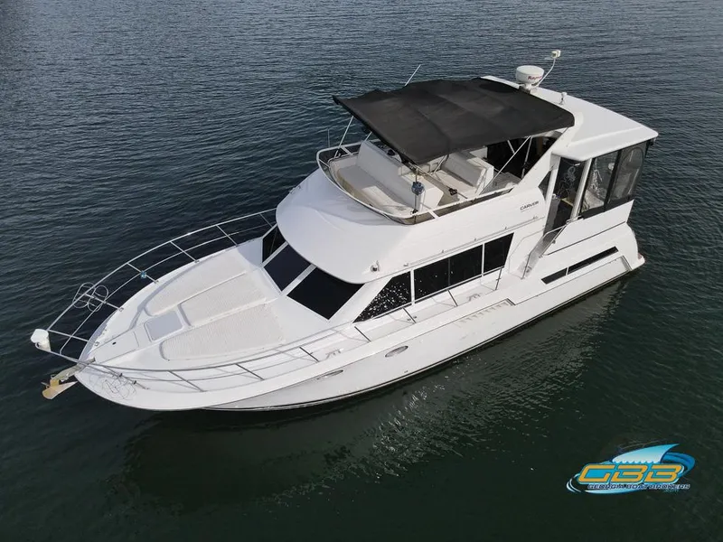 Slide: The Image of 1998 Carver 405 Aft Cabin yacht on calm water, featuring spacious deck and sleek design. - 12